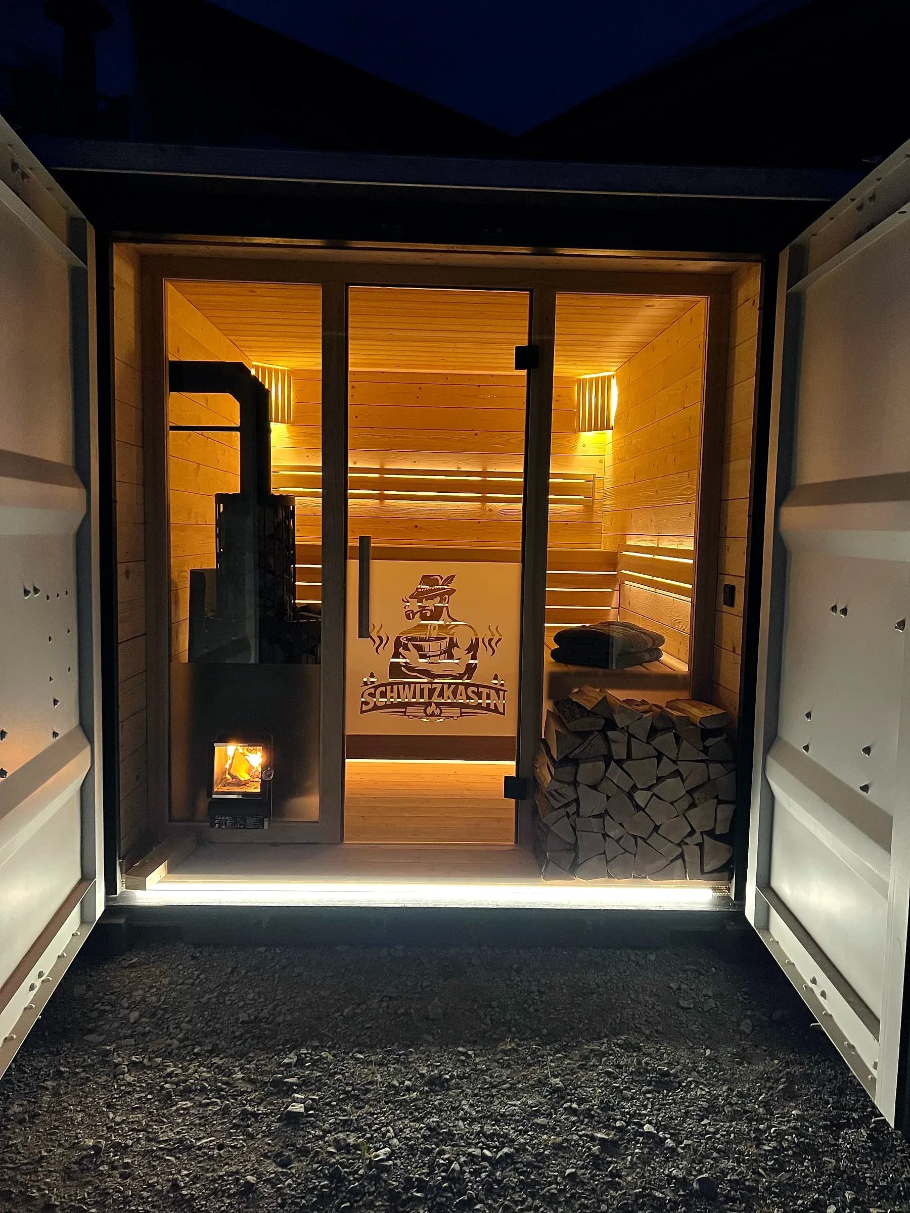 Schwitzkastn Mietsauna in Abendstimmung mit warmem Licht aus der geöffneten Tür