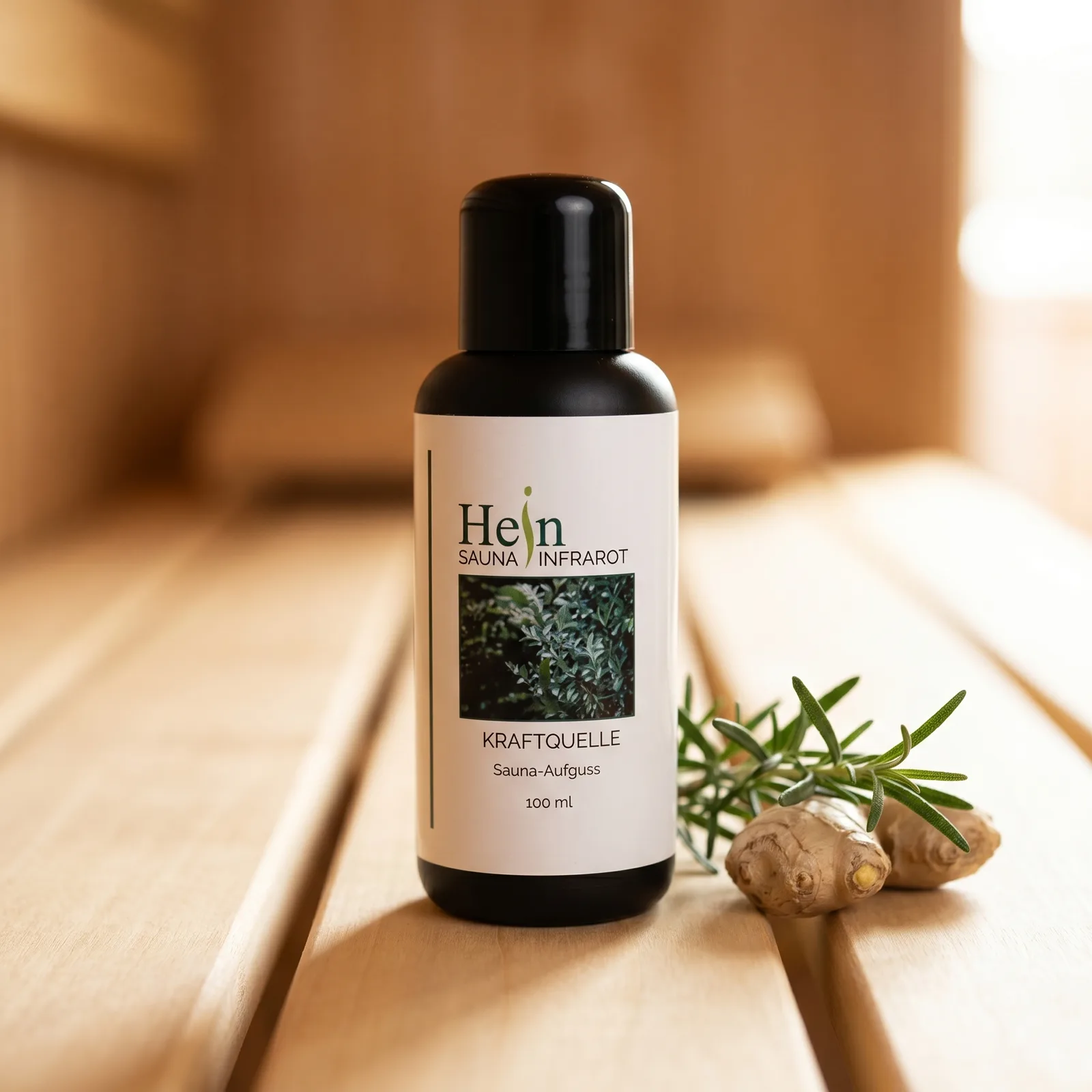 Hein Kraftquelle Sauna-Aufguss 100 ml, schwarze Flasche mit weißem Etikett auf Saunaholz mit Rosmarin und Ingwer