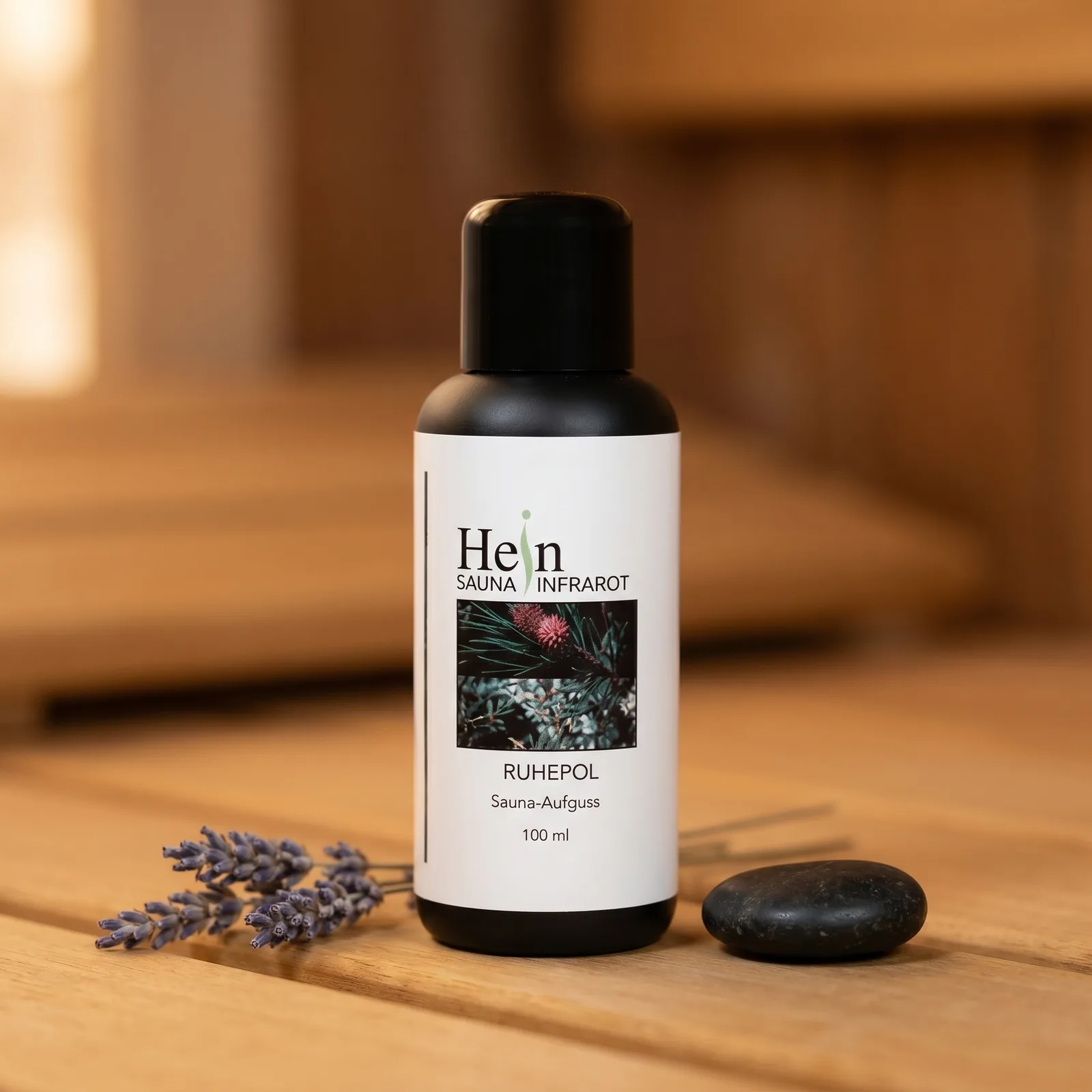 Hein Ruhepol Sauna-Aufguss 100 ml, schwarze Flasche mit weißem Etikett auf Saunaholz mit Lavendelzweigen
