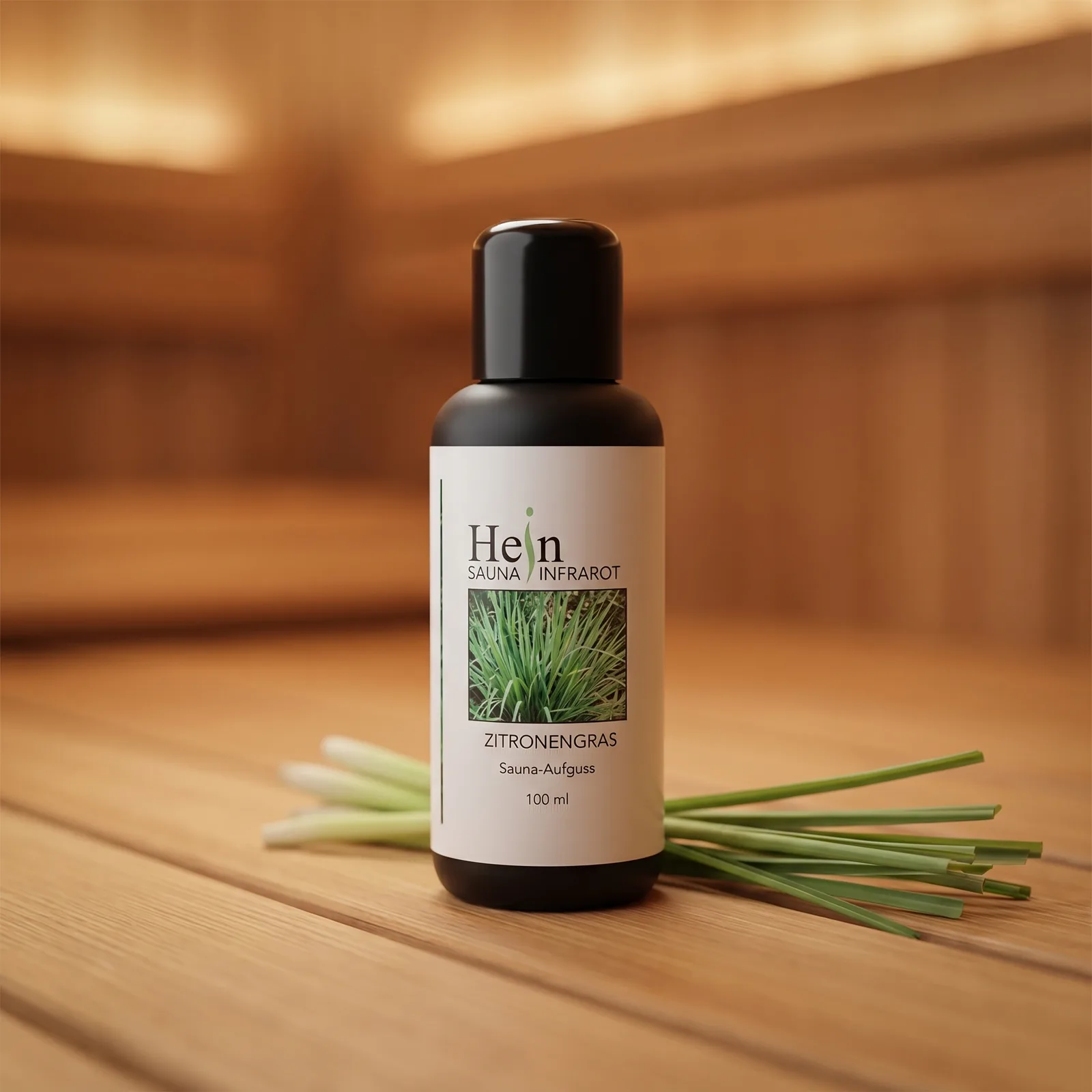 Hein Zitronengras Sauna-Aufguss 100 ml, schwarze Flasche mit weißem Etikett auf Saunaholz mit frischen Zitronengras-Halmen