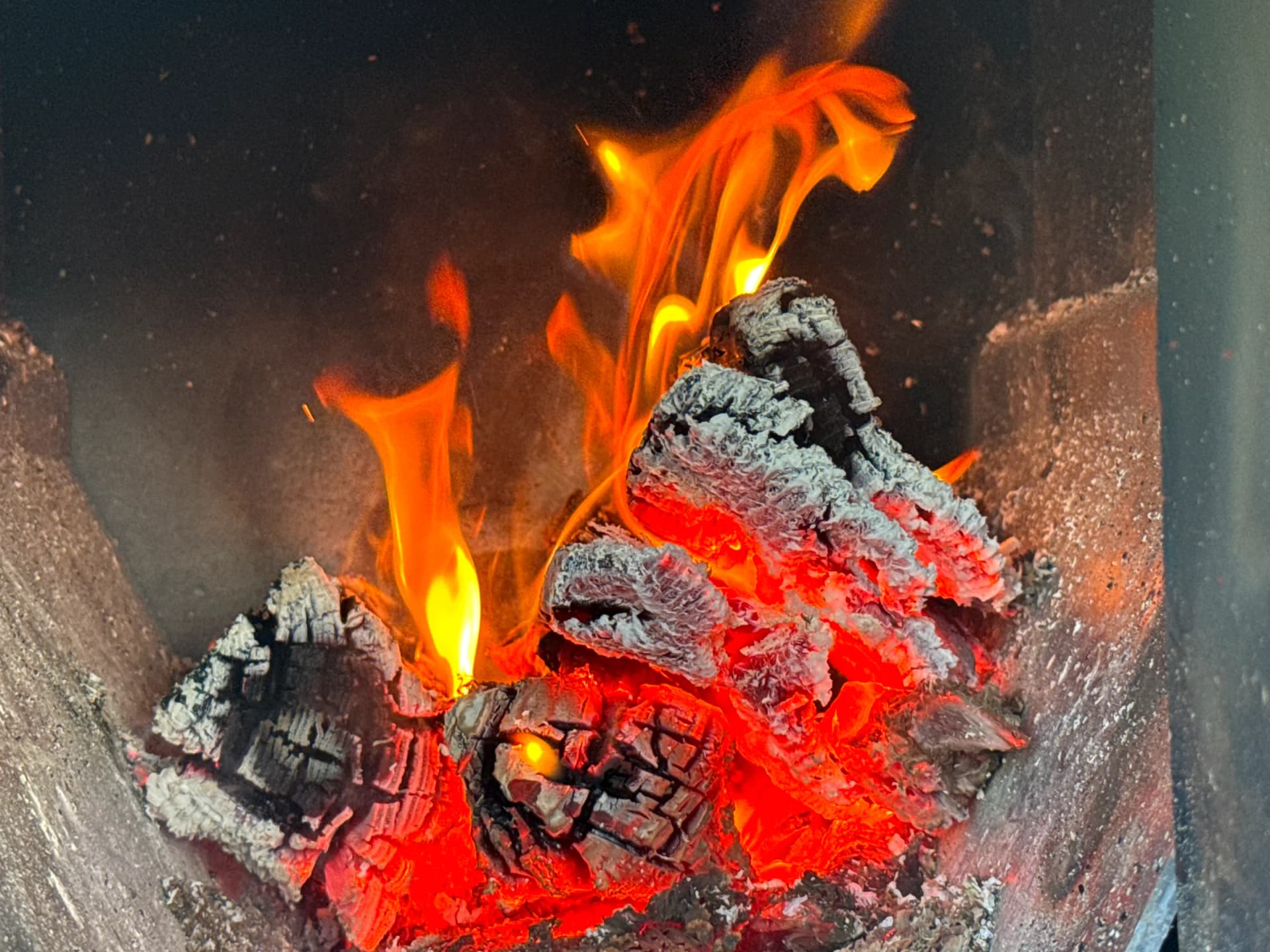 Glühende Holzscheite und lodernde Flammen im Holzofen des Schwitzkastn
