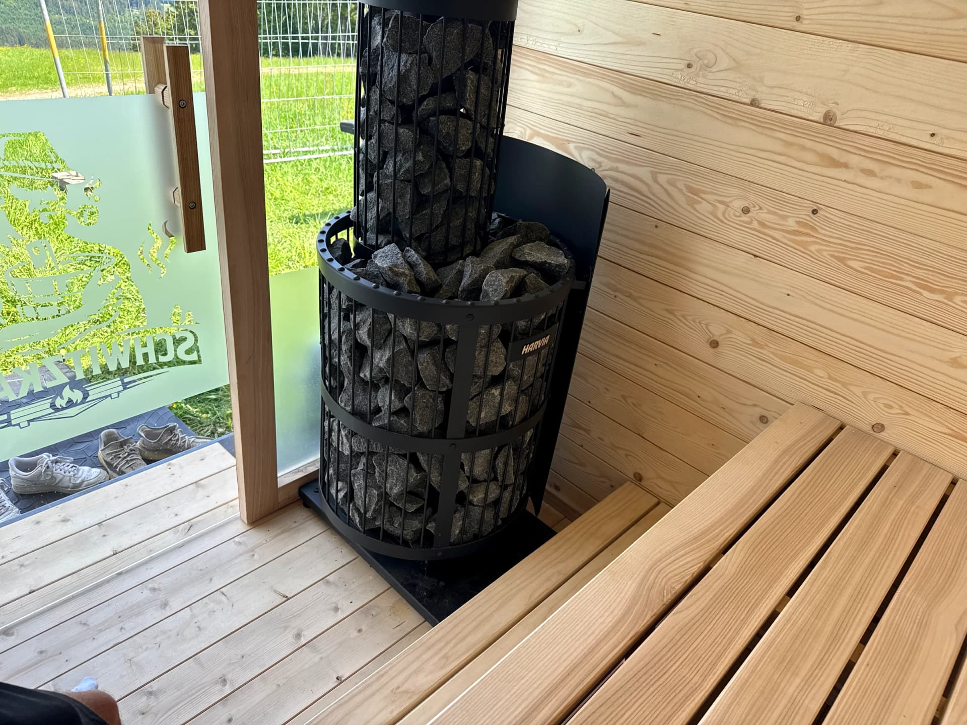 Harvia-Saunaofen mit Saunasteinen und massiver Holzbank im Schwitzkastn-Innenraum
